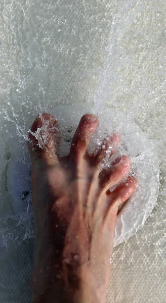 foot of man in the whirlpool in the pool with a powerful jet of water