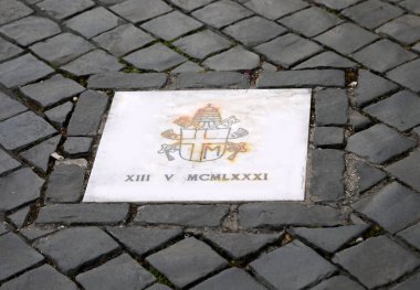 Papa 16. Benedikt 'in yaptığı plaket, John Paul' un armasını taşıyan saldırının yapıldığı yer ve 13 Mayıs 1981 tarihli Roma rakamları.