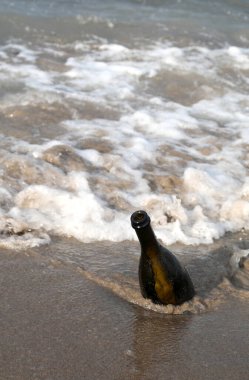 Deniz kenarında kumsalın altında ıssız cam bir şişe.