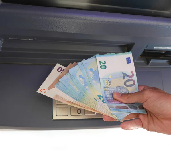 ATM and hand with euro banknotes in european city