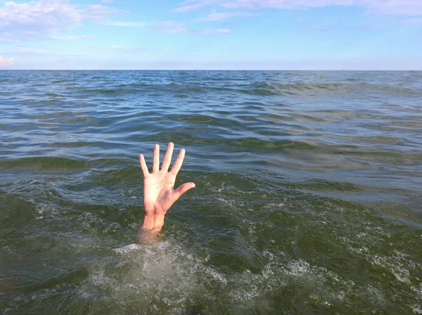 hand of the young man in distress who drowns in the middle of the sea