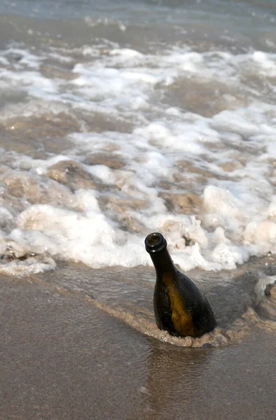 Isolated glass bottle by the sea under the sand of the beach