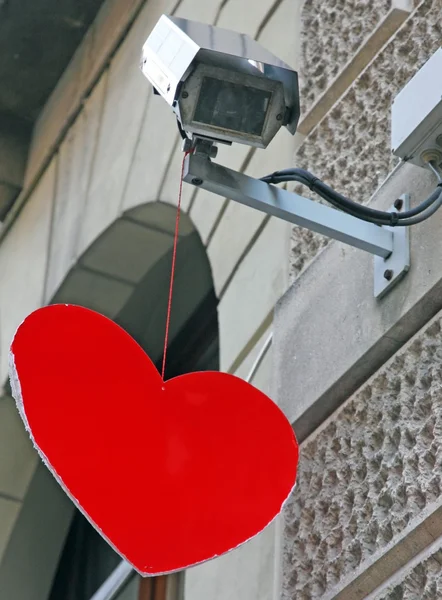 Corazón rojo colgando de una cámara de vigilancia — Foto de Stock