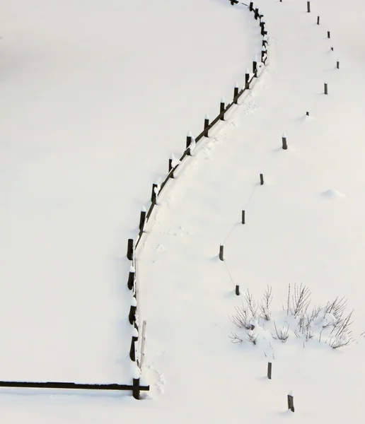 Дерев'яний паркан контрастує зі свіжим лугом холодним білим снігом — стокове фото