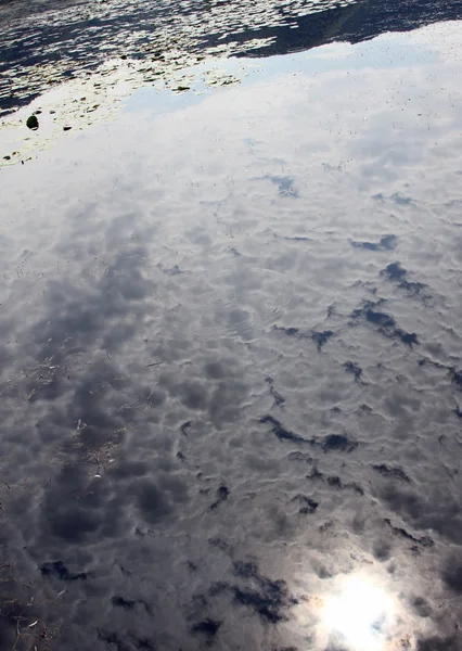 在湖的黑暗水域反射云和太阳 — 图库照片