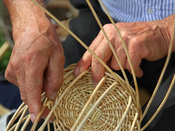 Hände der erfahrenen Handwerker machen ein Weidenkorb