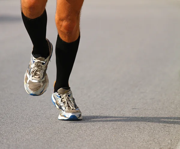 Corredor con zapatillas de deporte durante el maratón en carretera pavimentada — Foto de Stock