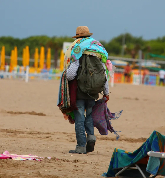 Образливий педлер з тканинами і сукнями, що ходять на пляжі гл — стокове фото