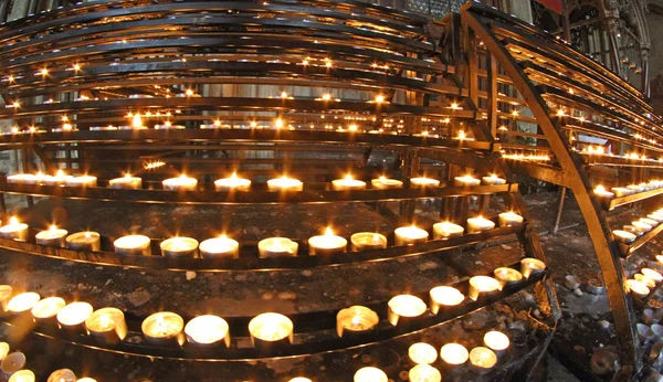 Kandelaar in kerk met vele wax kaarsen en flakkerende vlam — Stockfoto