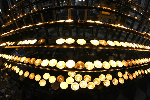 Kandelaar in kerk met vele wax kaarsen en flakkerende vlam — Stockfoto