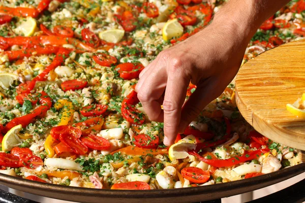 Cocinar añade rodajas de limón a la paella — Foto de Stock