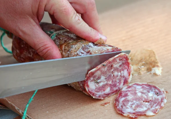 Cook's hand slicing the salami — Stock Photo, Image