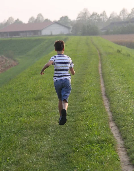 Criança corre ao longo de uma estrada rural — Fotografia de Stock