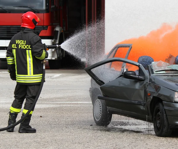 Tűzoltó, sisak, ki az autó égett a hab — Stock Fotó