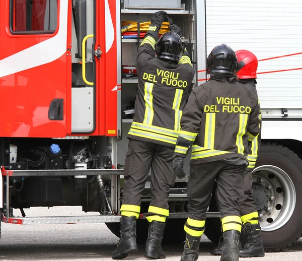 Пожарные, работающие рядом с пожарной машиной при обработке выхода — стоковое фото