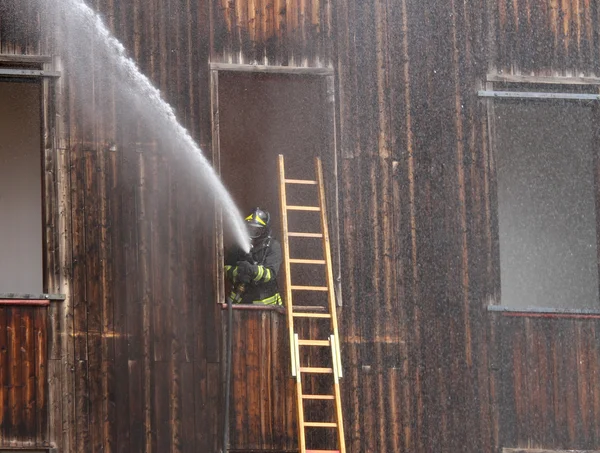 Fireman extinguish a fire with a hose — Stock Photo, Image