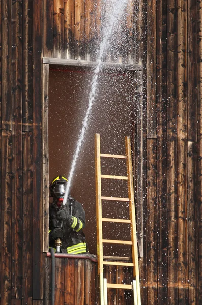 Pompier éteindre un feu avec un tuyau — Photo