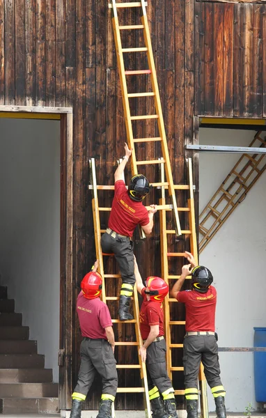 Firefighters during the fire drill mount fast wooden ladder — Stock Photo, Image