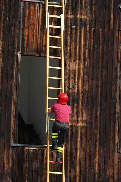 Pompiere durante una dimostrazione di utilizzare la scala per raggiungere il — Foto Stock