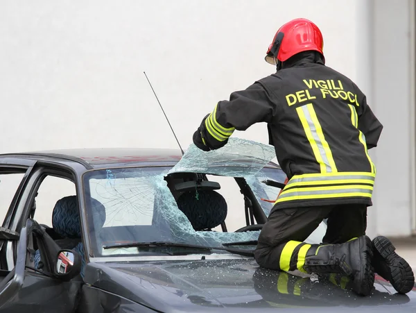 İtalyan itfaiyeciler i serbest bırakmak için arabanın ön camı kırmak — Stok fotoğraf