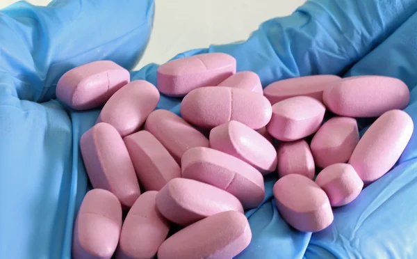Az a-vitamin-gyógyítás orvos kék kesztyű Pink alátét — Stock Fotó