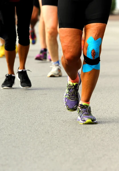 Athlete with knee bandaged by medical bandage during the Maratho — Stock Photo, Image