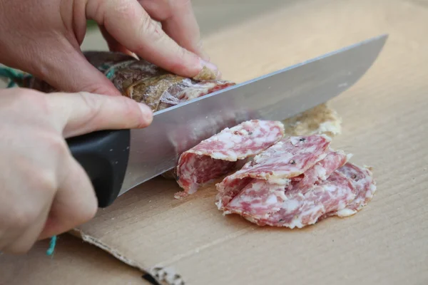 MAN slicing the salami with sharp knife — Stock Photo, Image