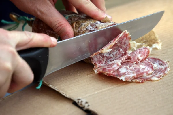 MAN slicing the salami with sharp knife — Stock Photo, Image