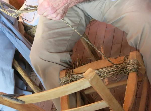 Homem idoso qualificados linha strawbedder de madeira velha e rattan chai — Fotografia de Stock
