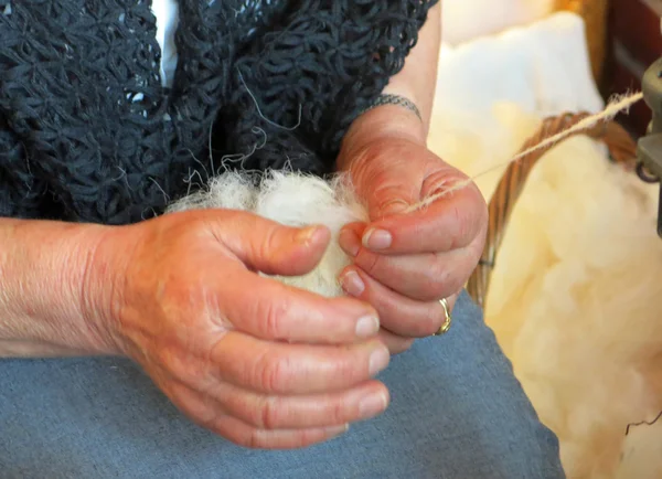 Mulher idosa trabalha a lã com uma roda de fiação antiga — Fotografia de Stock