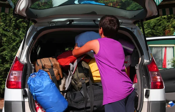 Niño con camiseta púrpura cargo de equipaje de coche —  Fotos de Stock