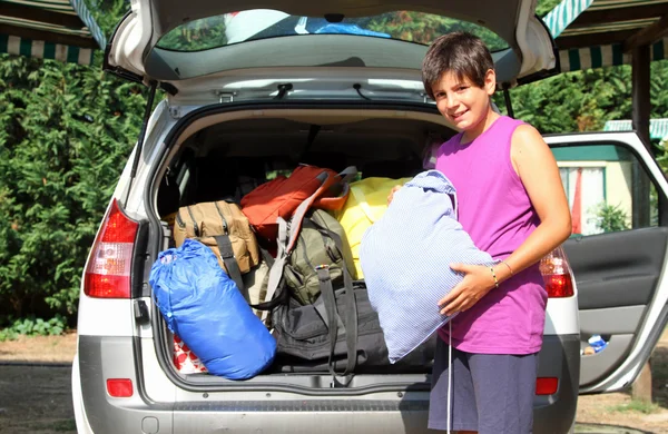 Niño con camisa púrpura cargo de equipaje de coche antes de la salida —  Fotos de Stock