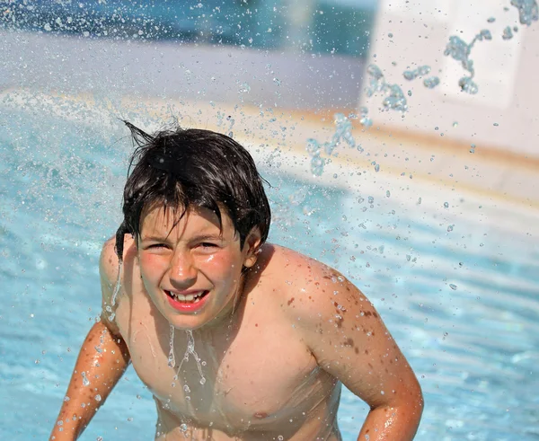 Garçon sous le puissant jet d'eau dans la piscine en été — Photo