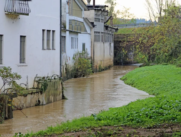 Řeka se spoustou bláta poblíž městské domy — Stock fotografie