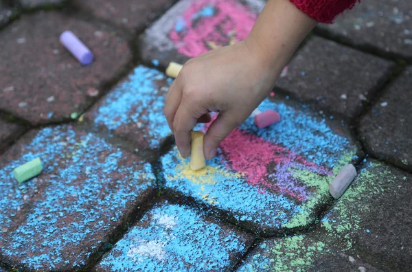 Joven chica dibuja con la tiza de colores en el camino — Foto de Stock