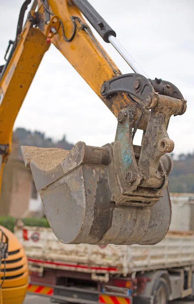 Cubo de una excavadora y un camión en el fondo — Foto de Stock