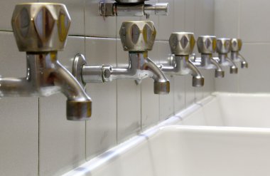 musluklar sıralı ve beyaz seramik bir lavabo