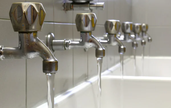 Grifos de acero con chorro de agua en fregadero de cerámica — Foto de Stock