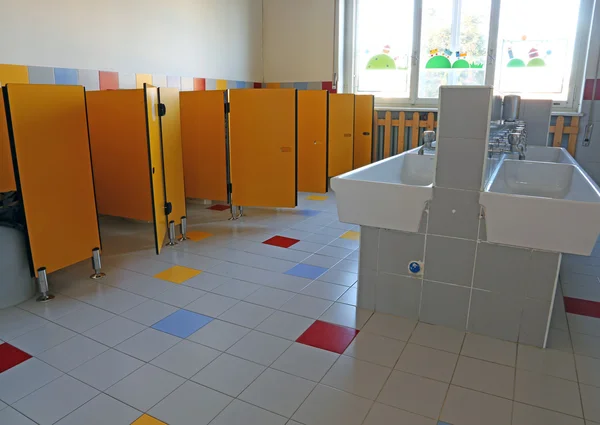 Bathroom of the nursery school with white ceramic sinks and door — Stock Photo, Image