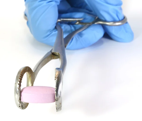 Pilule rose avec pinces médicales et le gant du médecin — Photo