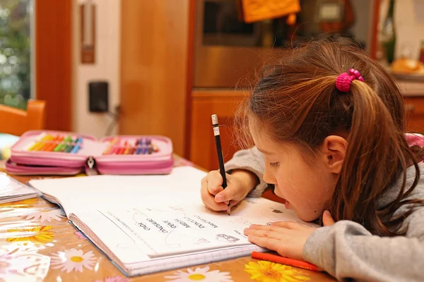 Küçük kız ödev defter üzerinde yazar. — Stok fotoğraf