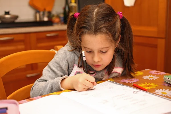 Güzel küçük bir kız ile kalem defter egzersizleri üzerinde yazıyor. — Stok fotoğraf