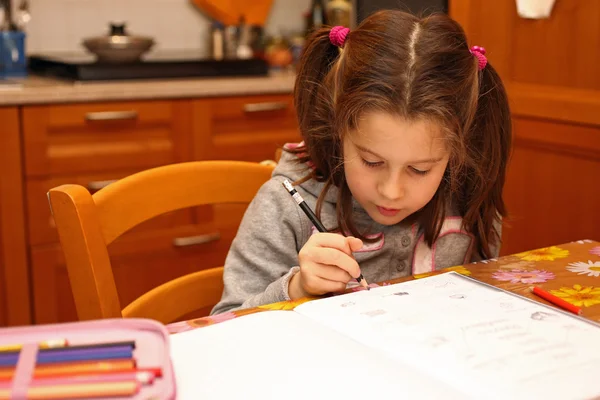 Kleines Mädchen schreibt mit Bleistift an Schulaufgaben — Stockfoto