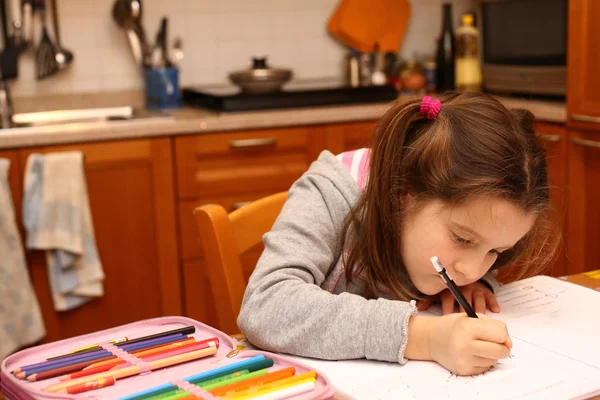 Csinos lány írja ceruzával vele házi feladatot a konyhában — Stock Fotó