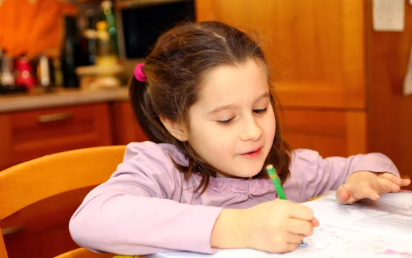 Cute little girl writes on her notebook at home — Stock Photo, Image