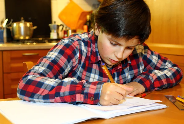 Niño escribe en su cuaderno en casa — Foto de Stock