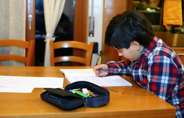 Young boy writes on his notebook at home — Stock Photo, Image