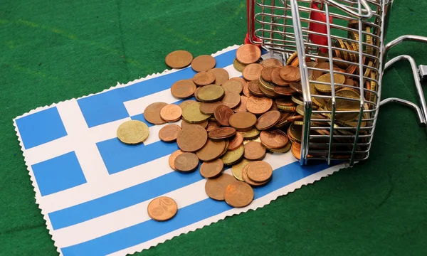 Einkaufswagen voller Münzen Euro über Flagge Griechenlands gestürzt — Stockfoto