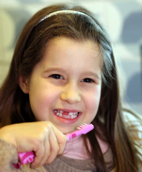 Ung flicka utan en tand när du borstar tänderna i badrummet — Stockfoto