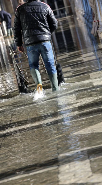 Operaio con il carrello di trasporto in alta marea a Venezia — Foto Stock